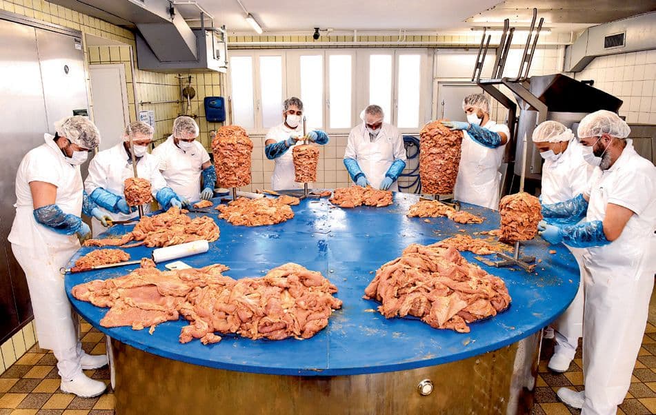 Das Produktionsteam schichtet Fleisch an einem runden Arbeitstisch